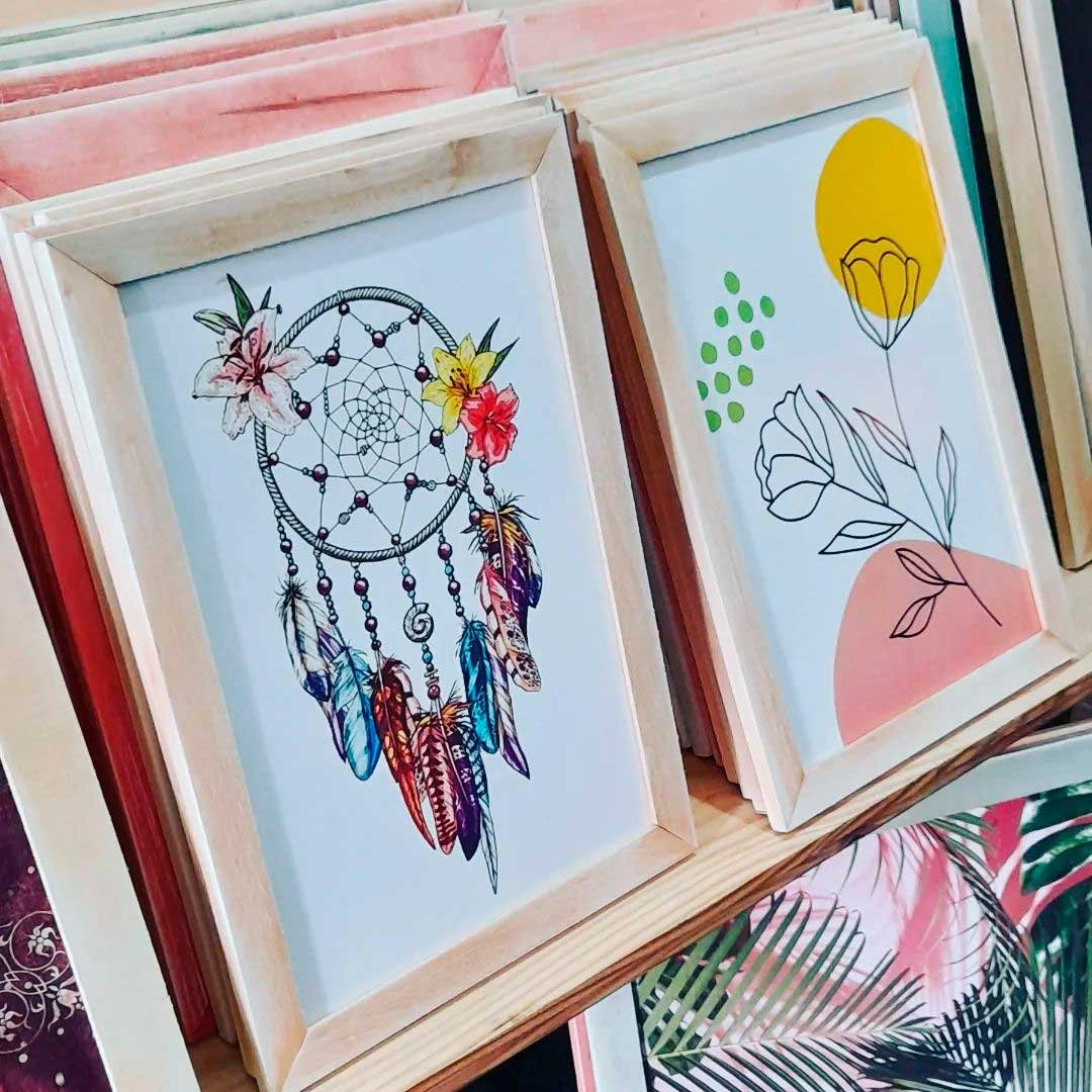 cuadros decorativos en exhibicion en el local. ilustracion de atrapasueños y otro de floresy colores
